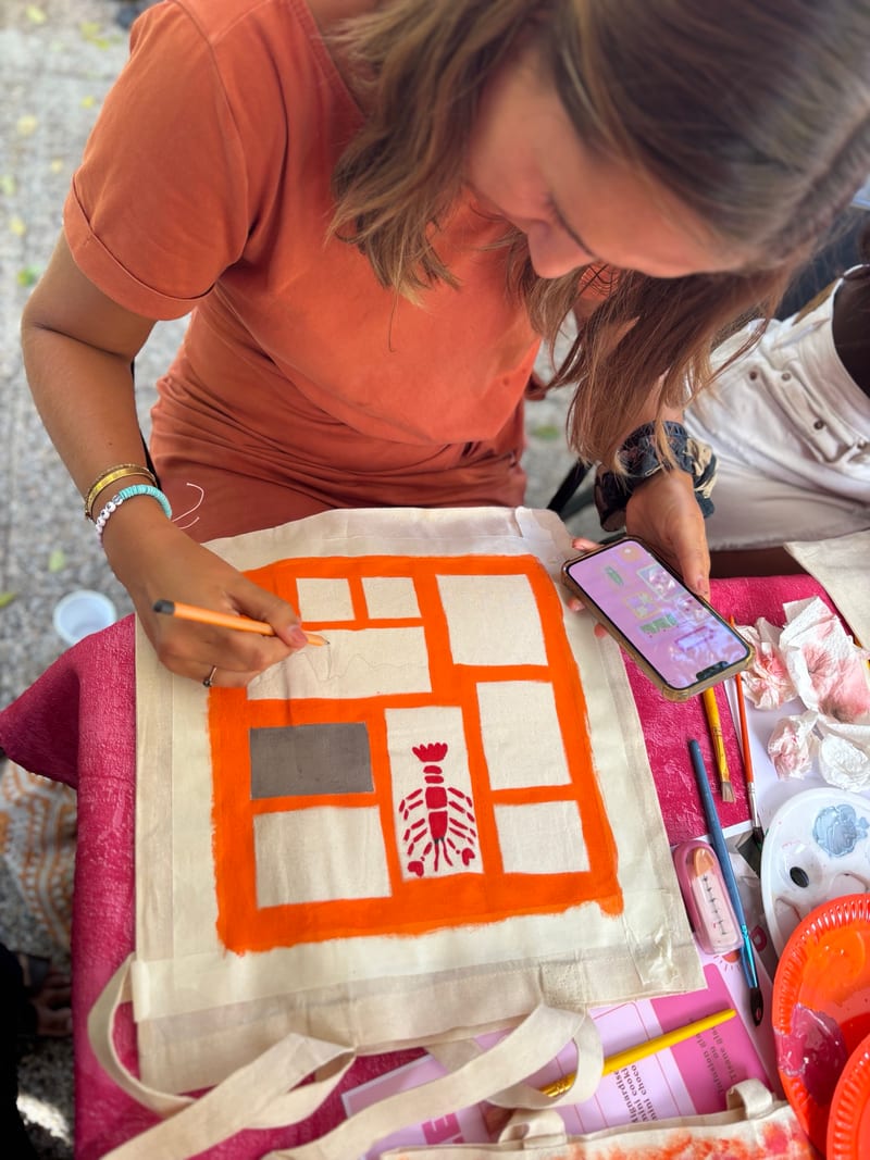 Participante peignant un tote bag aux motifs orange et rouge
