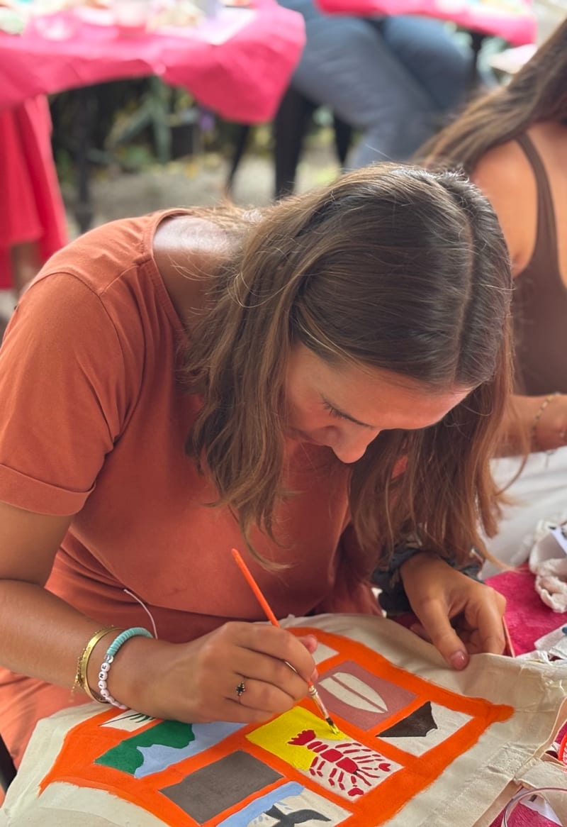 Gros plan d’un pinceau qui peint un tote bag orange