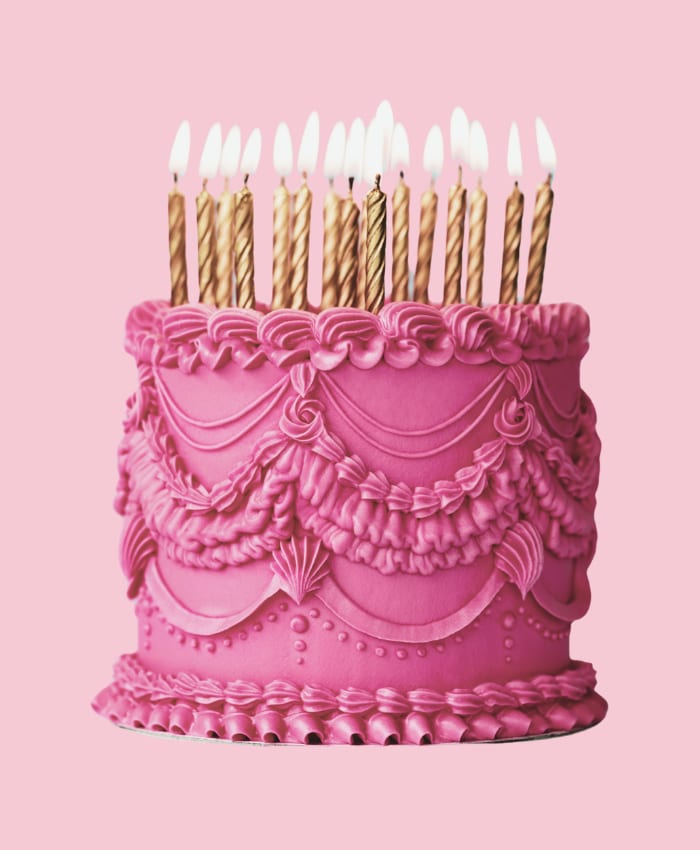 Gâteau d’anniversaire rose à décor de crème, garni de bougies dorées